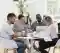 grupo diverso de pessoas setados em uma mesa